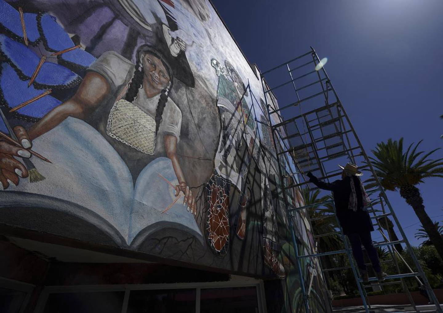 La muralista mexicana Yanet Calderón pinta en la fachada de un edificio municipal en San Salvador, México, el sábado 30 de julio de 2022. Calderón es parte de un grupo de artistas que buscan revivir el muralismo, un movimiento que puso a México a la vanguardia mundial del arte hace un siglo. (Foto AP/Fernando Llano)