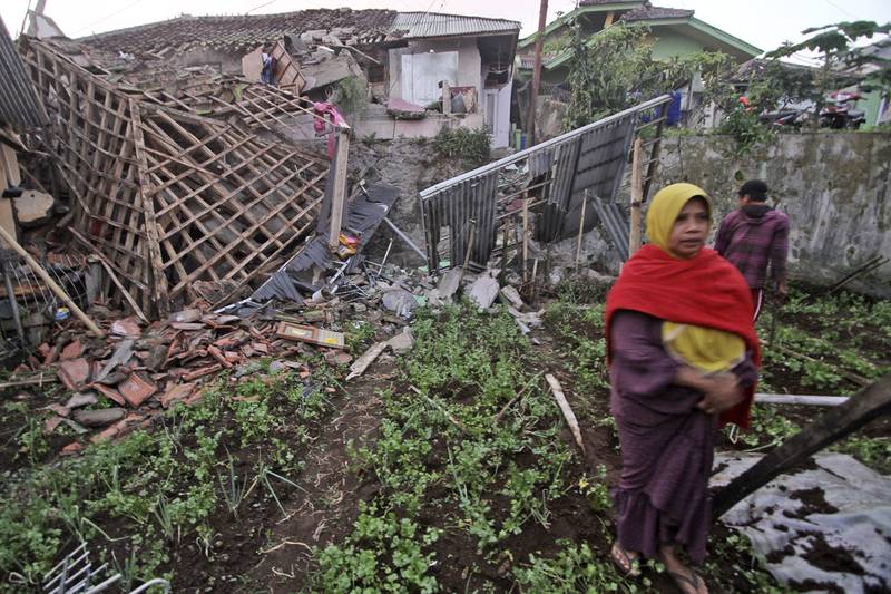Una mujer camina frente a una vivienda dañada por un sismo en Cianjur