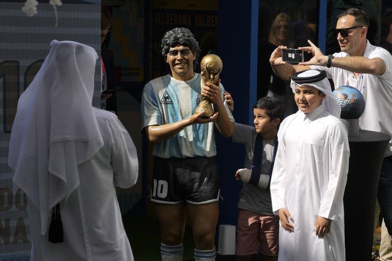 Un grupo de niños posan junto a una estatua de Diego Maradona durante una conmemoración en su honor en Doha, Qatar, el 25 de noviembre de 2022