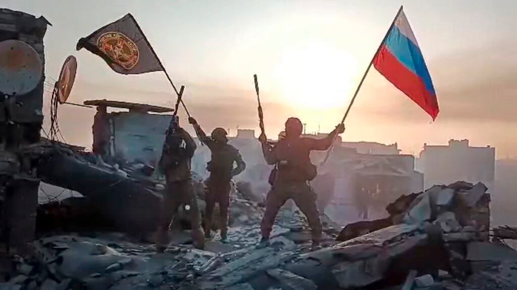 Soldados del Grupo Wagner ondean una bandera de Rusia y del grupo sobre un edificio dañado en Bájmut, Ucrania (AP).