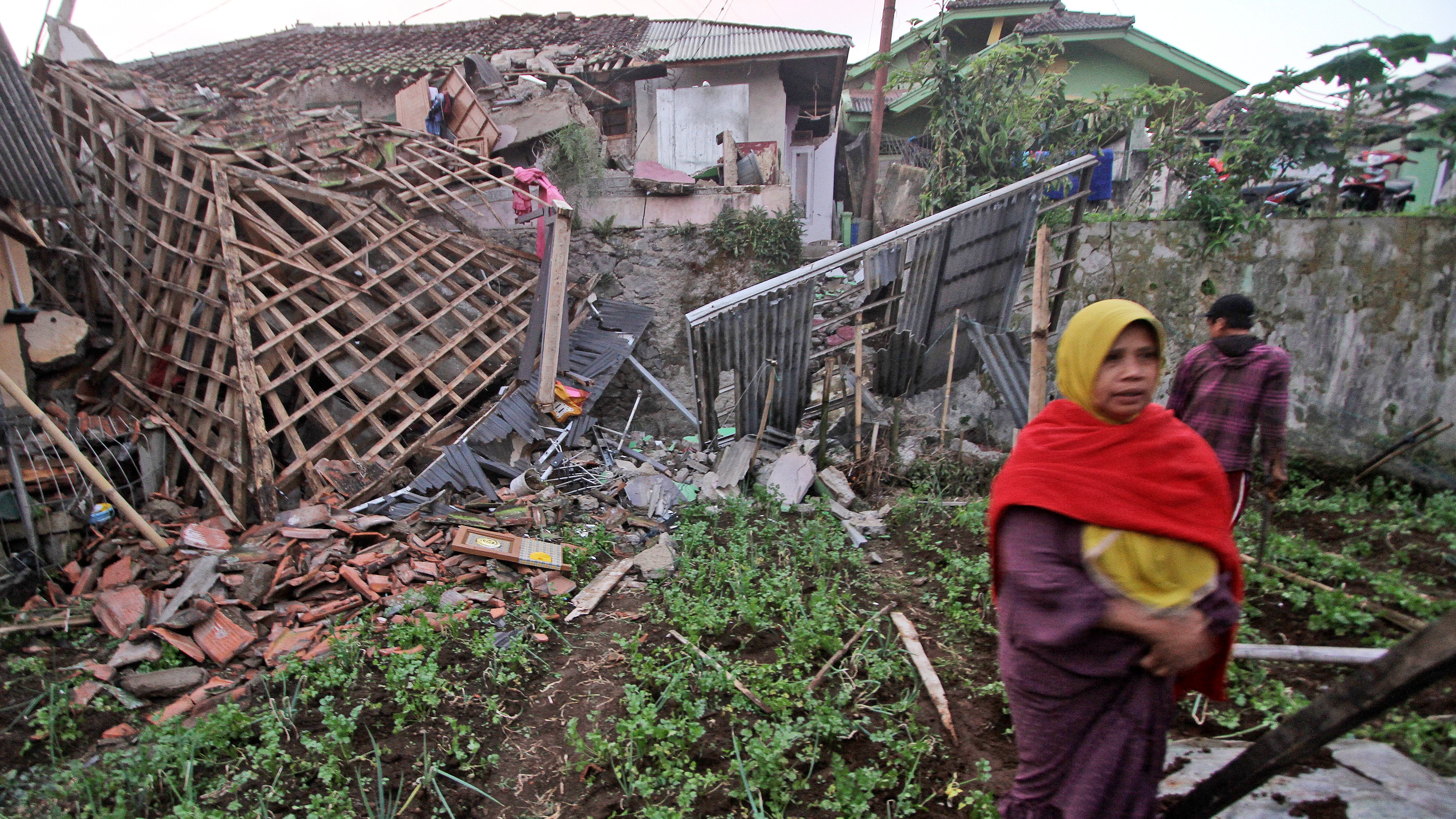 Una mujer camina frente a una vivienda dañada por un sismo en Cianjur